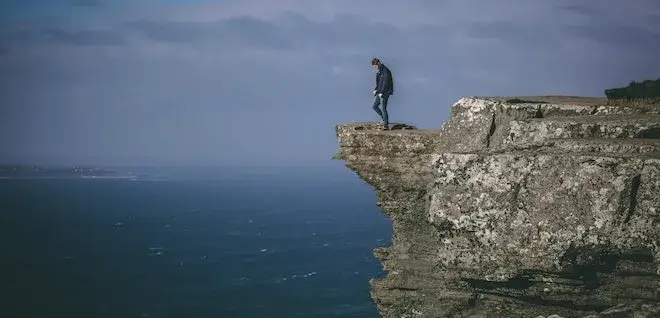 Image of a man standing on a cliff overlooking the sea